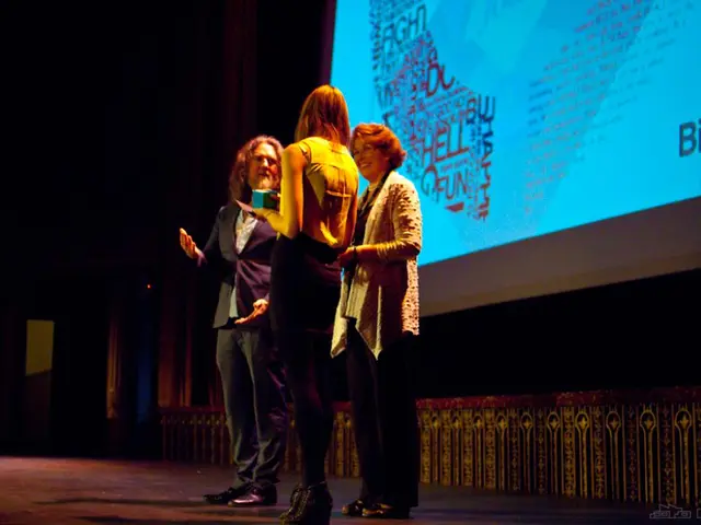 This is an image clicked in the dark. Here I can see three persons standing on the stage facing...