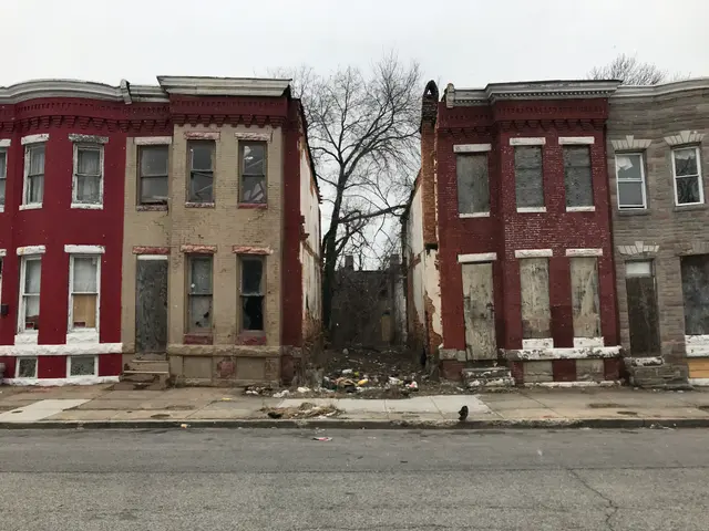 The image shows a row of abandoned buildings on the corner of a street, with a road at the bottom,...