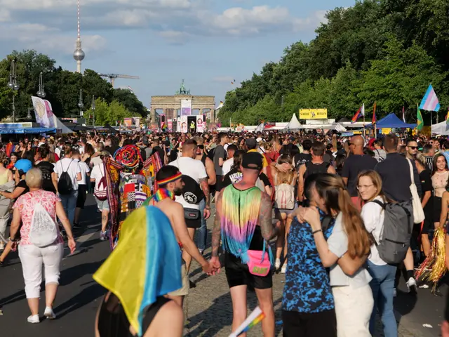 The image shows a large crowd of people walking down a street in Berlin, Germany. Many of them are...