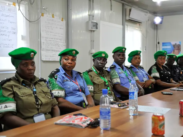 The image shows a group of police officers sitting around a long table. They are wearing uniforms...