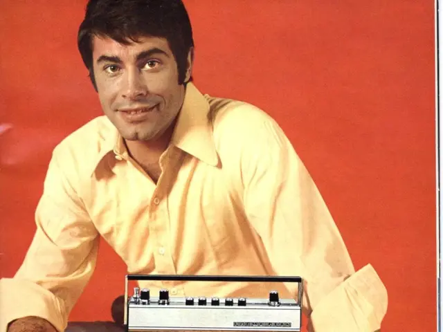 The image shows an advertisement for a Loewe Opta radio featuring a man sitting in front of it. The...