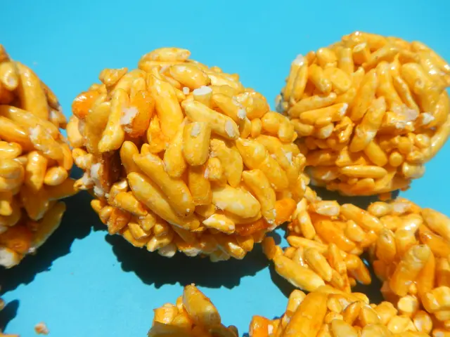 The image shows a close up of a pile of yellow rice krispy treats on a blue surface. The treats...