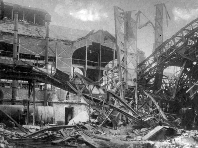 The image shows a black and white photo of a building that has been demolished, with a bridge in...