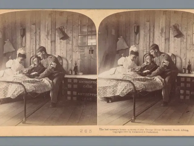 The image shows an old black and white photo of a group of people in a hospital room. There are two...