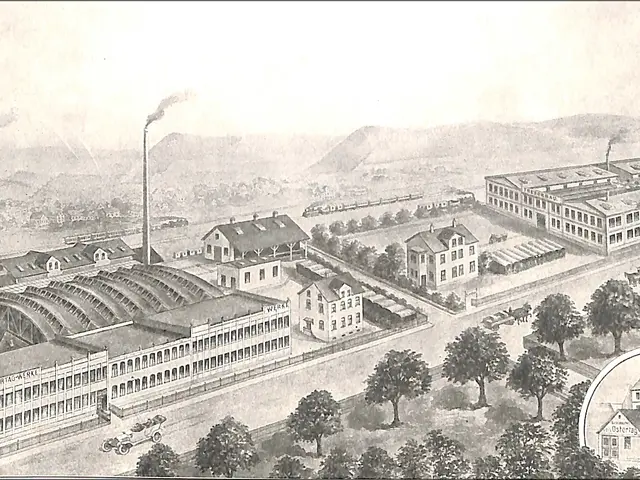 The image shows an aerial view of a city with lots of buildings, trees, vehicles on the road,...