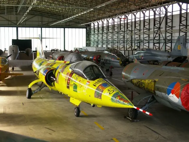 The image shows a large hangar filled with lots of fighter jets, with a floor at the bottom, a...