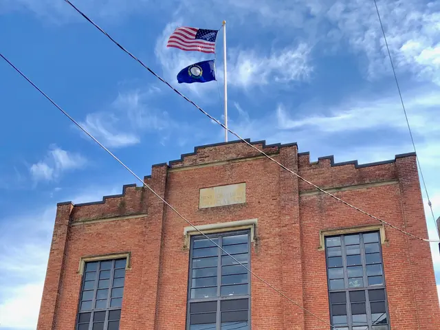 The image shows a brick building with a flag on top of it, surrounded by windows, a door, a name...