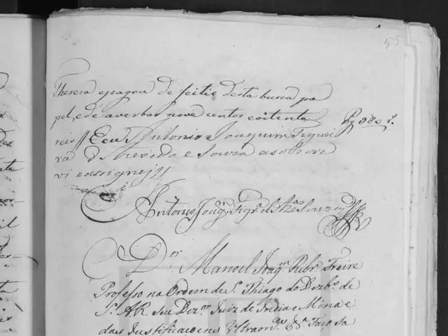 The image shows an open book with handwriting on it in black and white. The text on the book reads...