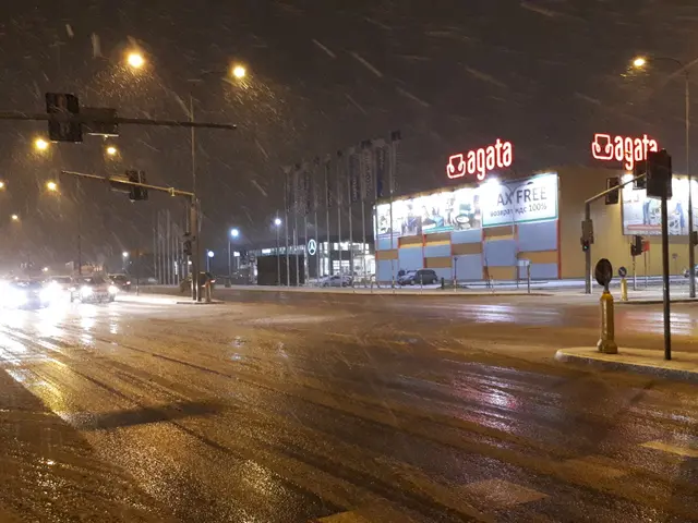 The image shows a city street at night with cars driving down it, illuminated by street lights and...