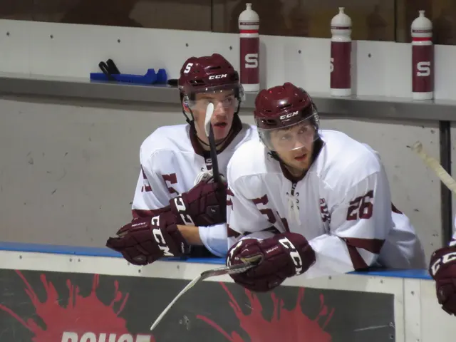 The image shows a group of young men playing a game of ice hockey. They are wearing helmets and...