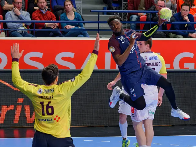 The image shows a group of men playing a game of handball on a court, with a ball in the air. In...