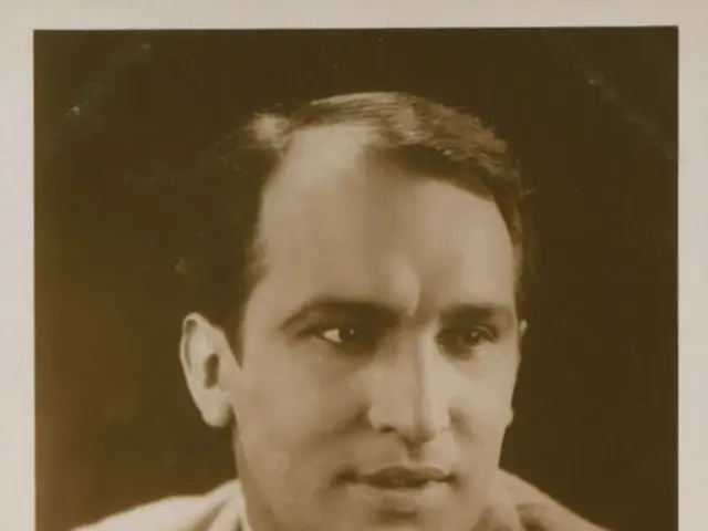 The image shows a black and white photo of Wilhelm Dieterle, a German composer, wearing a blazer...