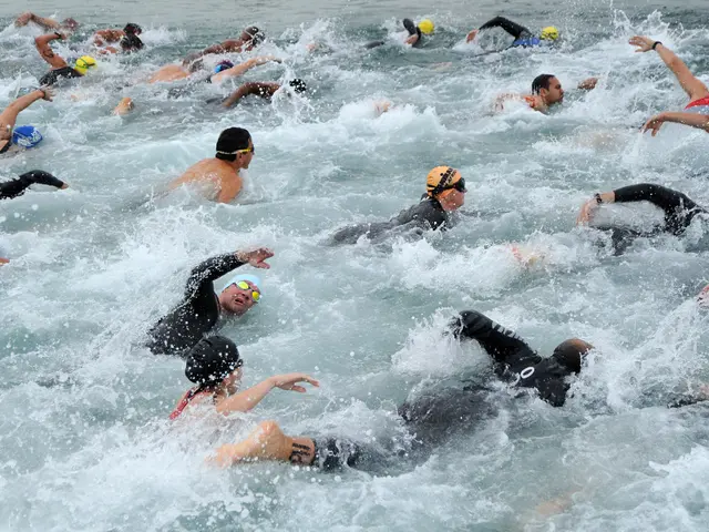 The image shows a group of people swimming in a body of water, wearing swimming caps and goggles....