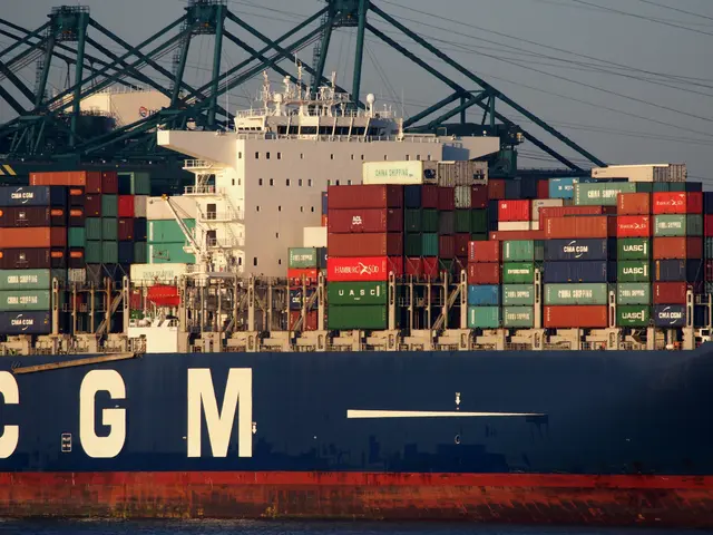 The image shows a large container ship docked in the water near a dock, with a number of containers...