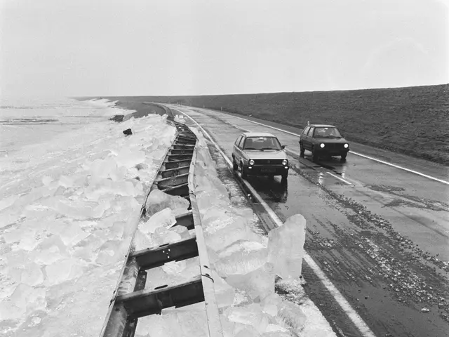 The image shows a black and white photo of two cars driving down a road covered in ice, with a...