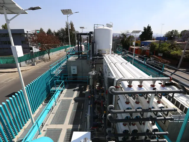 The image shows a large water treatment plant with pipes and valves on the side of it, surrounded...