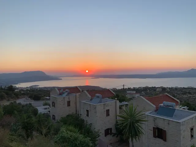 The image shows a stunning view of the sun setting over the ocean from the top of a hill. I can see...