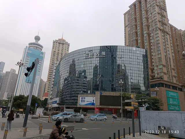 The image shows a bustling city street with tall buildings in the background, vehicles on the road,...