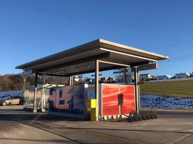 The image shows a bus stop with a car parked in front of it, surrounded by poles, lights, boards,...