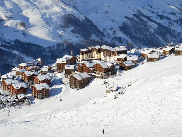 The image shows a picturesque view of a ski resort in the French Alps, with snow-covered mountains...
