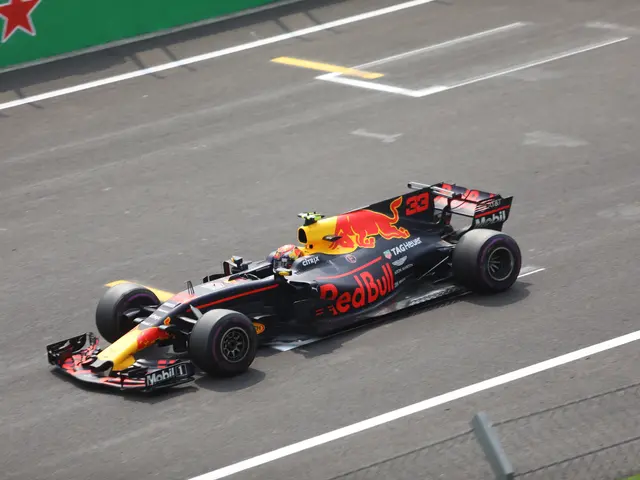The image shows Max Verstappen driving a Red Bull Racing RB15 car on the road, with a fence and...