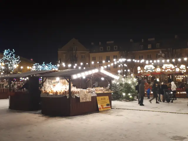 The image shows a bustling Christmas market in the middle of a snowy street at night. We can see a...