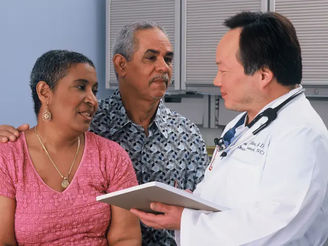 The image shows a doctor talking to a woman and a man in a hospital room. The doctor is wearing a...