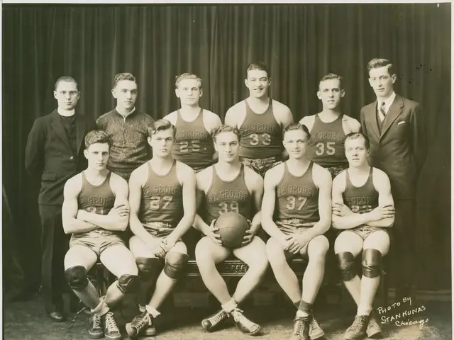 The image shows a black and white photo of a basketball team, with a man sitting on a bench holding...