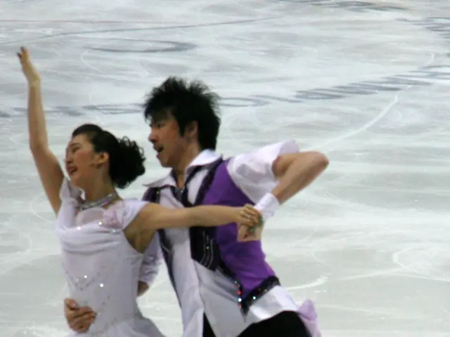 The image shows a man and a woman figure skating on an ice rink, gracefully gliding across the ice...