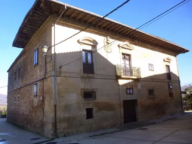 The image shows an old building with a lot of windows and a roof, a street lamp attached to a pole,...