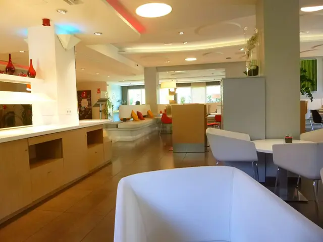 The image shows a large white couch sitting in the middle of a room with tables and chairs arranged...