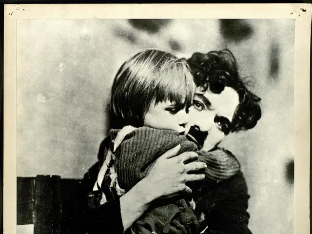 The image shows a black and white photo of Charlie Chaplin holding a child in his arms, with a...