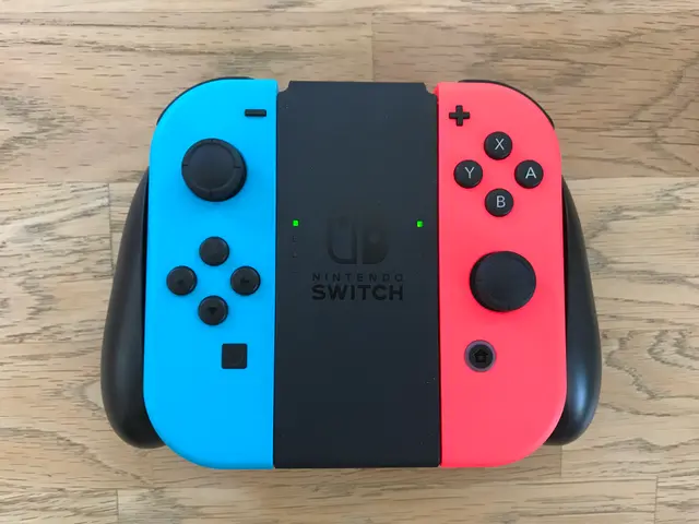 The image shows a Nintendo Switch Joy-Con in a combination of blue, red, and black colors resting...