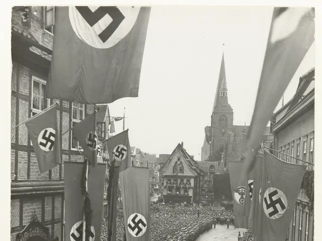 The image shows a large crowd of people walking down a street with Nazi flags, surrounded by...