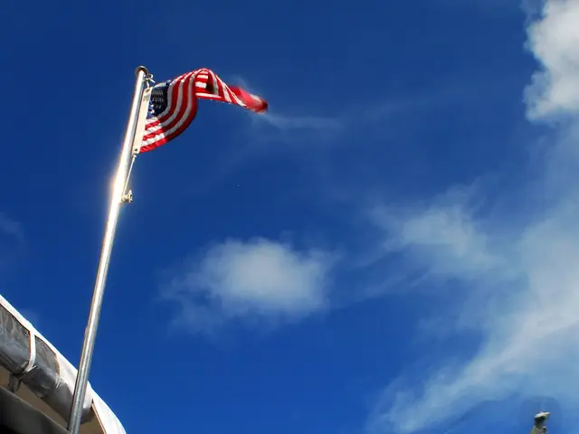 The image shows a helicopter flying in the air with a rope attached to it, flying over a hospital...