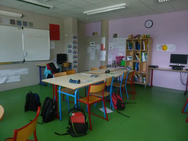 The image shows a classroom with tables and chairs arranged in it, bags on the floor, bookshelves...