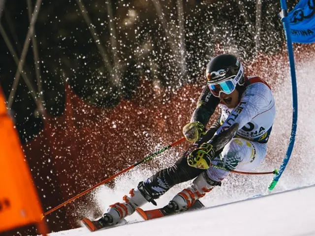 The image shows a skier wearing a helmet, goggles, gloves, and shoes, holding ski poles and racing...
