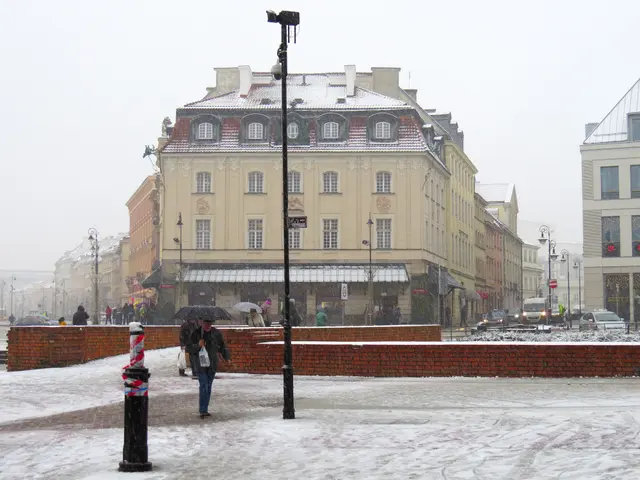 The image shows a group of people walking down a snow covered street in Warsaw, Poland. They are...