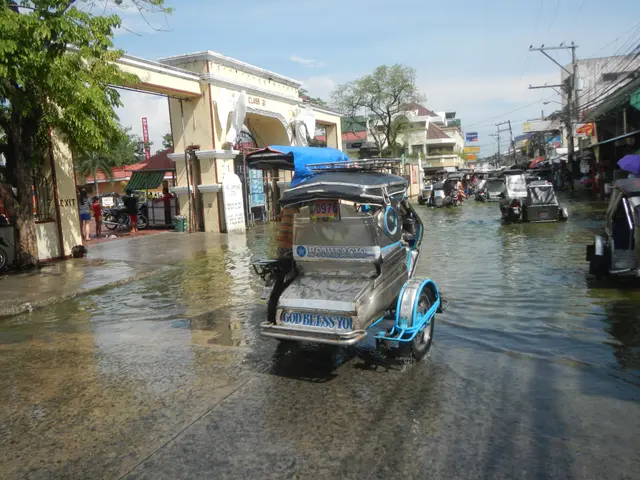 The image shows a tuk-tuk driving through a flooded street in the middle of a city, surrounded by...