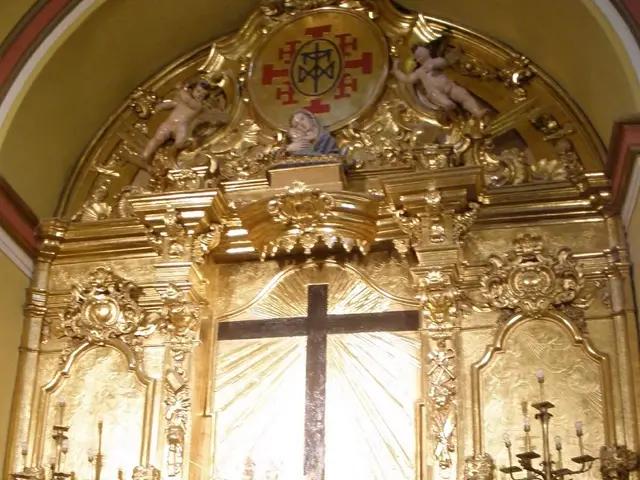 The image shows an altar in a church with a cross on it, surrounded by flower bouquets, candles...