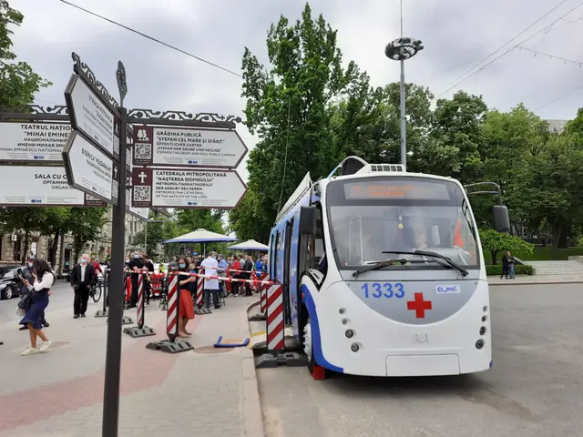The image shows a white and blue bus parked on the side of a street, surrounded by a group of...