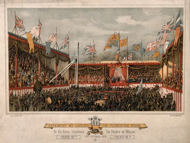 The image shows a large crowd of people standing in front of a stage, with flags waving in the...
