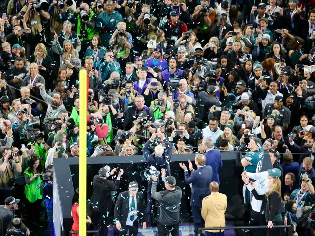 The image shows a group of people standing on top of a stage, some of them holding cameras and...