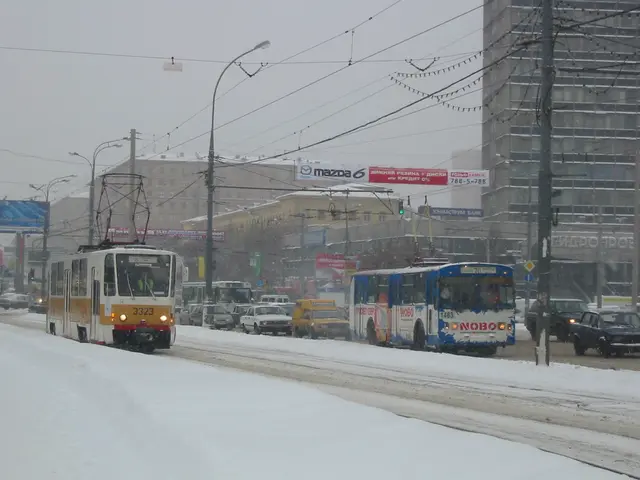 The image shows a city street filled with lots of traffic on a snowy day. We can see vehicles on...