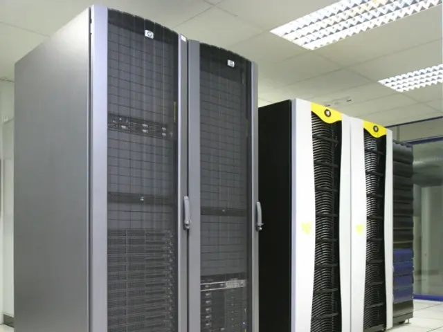 The image shows a row of servers in a data center, with the floor, ceiling, and lights visible. The...
