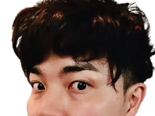 The image shows a man in a suit and tie looking directly at the camera against a white background....