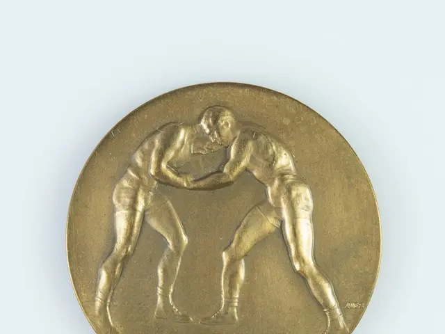 The image shows a gold medal with two men wrestling on it against a white background.