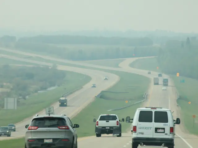 The image shows a highway filled with lots of traffic on a foggy day. There are vehicles on the...