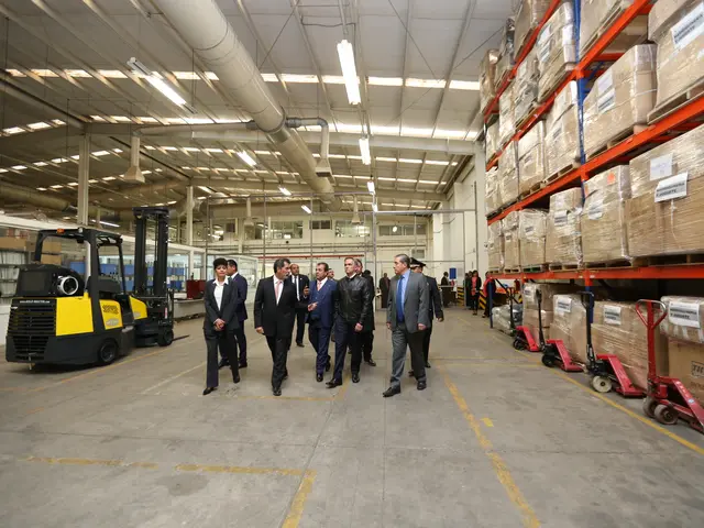 The image shows a group of men walking through a warehouse filled with boxes on the right side and...