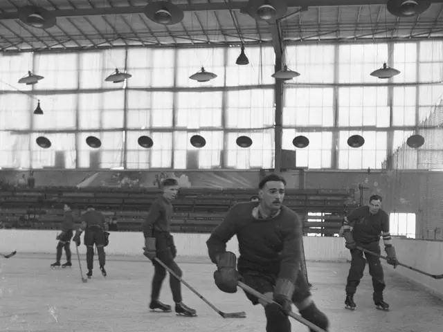 The image shows a group of men playing hockey on an ice rink, with a wall in the background and...